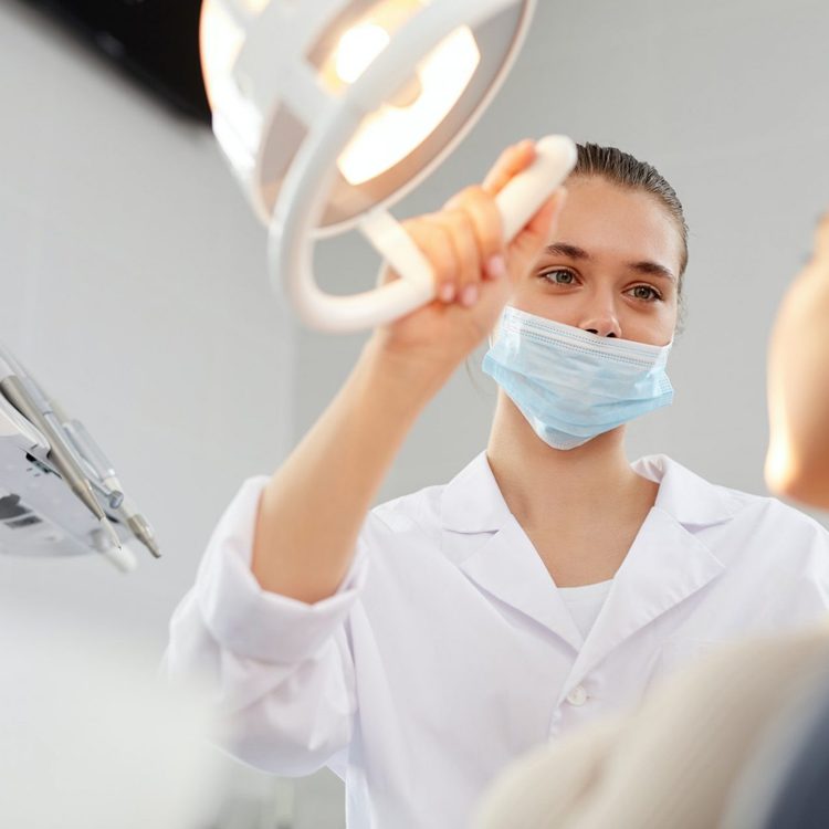 female-dentist-adjusting-lamp-e1617040195839